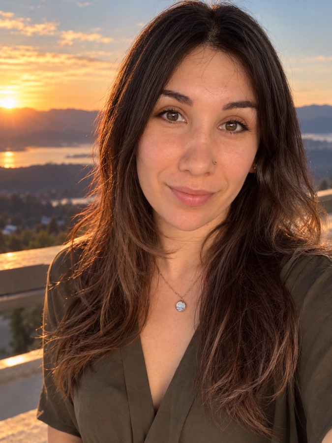 Nina Goluskin, smiling, with a sunset behind her.